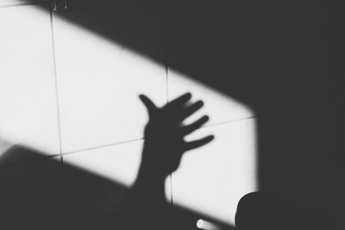 Schwarz-weiß Bild, Schatten einer Hand auf Fliesen.