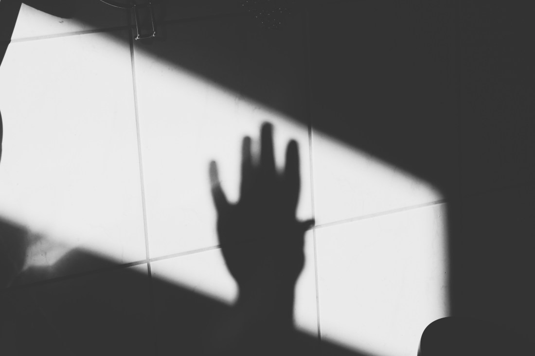 Schwarz-weiß Bild, Schatten einer Hand auf Fliesen.