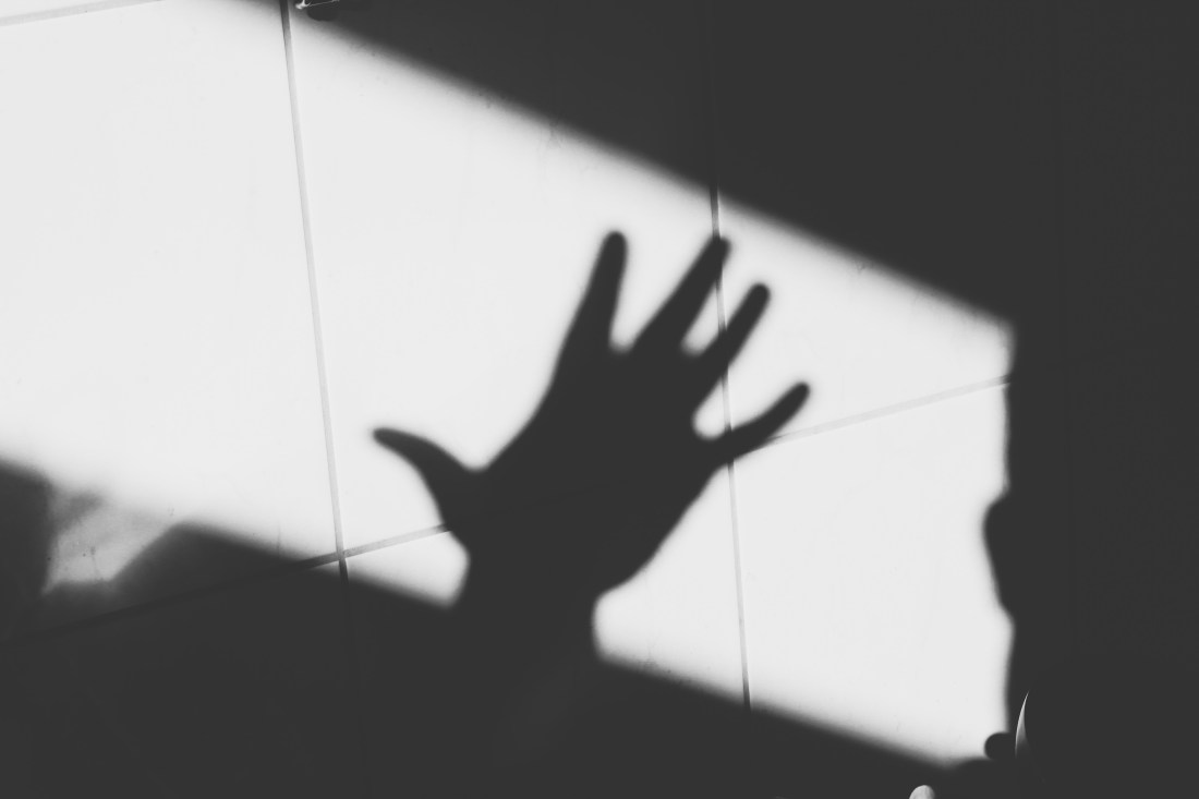 Schwarz-weiß Bild, Schatten einer Hand auf Fliesen.