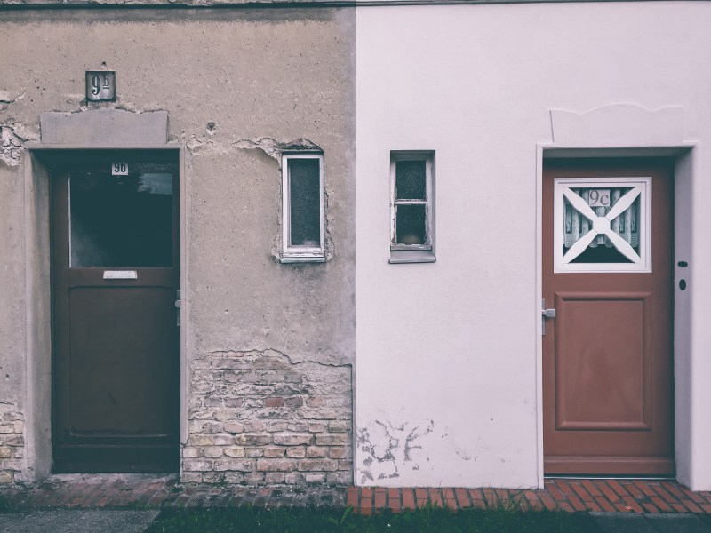 Gebäude mit zwei Türen, eine Hälfte des Gebäudes ist renoviert worden, die andere nicht, Putz bröckelt von den Wänden.