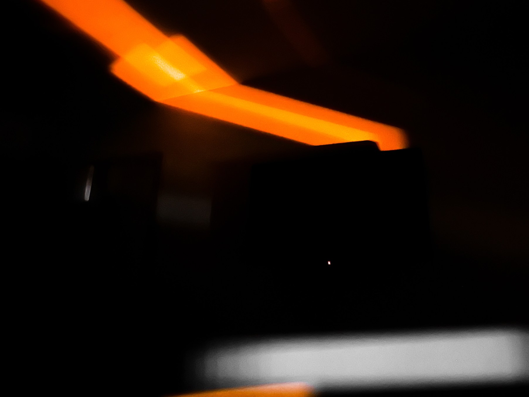 Dunkelheit durchzogen von weißen und orangefarbenen Lichtstreifen.